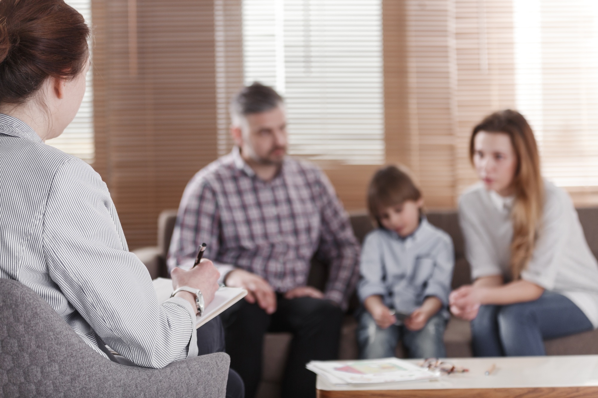 Rear view of female psychologist helping young family with a kid
